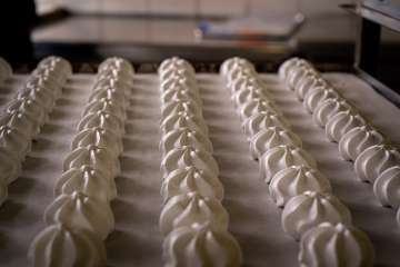 Retro-Aufnahme von Meringues: Geschäftsinhaber Christoph Frutiger bei der Arbeit: In der Frutal Versandbäckerei in Meiringen werden jedes Jahr über 30 Tonnen des süssen Schaumgebäcks aus Eiweiss und Zucker hergestellt.
