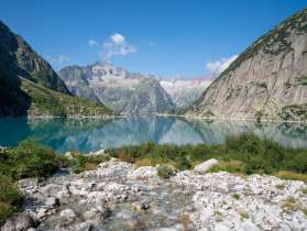 Nahaufnahme vom Gelmersee. Das türkisfarbene Wasser spiegelt die umliegenden Berggipfel auf der Wasseroberfläache.