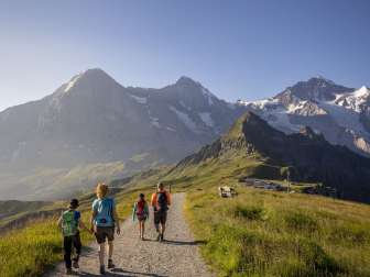 Eine Familie auf dem Royal Walk. Wanderung mit Aussicht auf den Männlichen und das Dreigestirn Eiger, Mönch und Jungfrau.