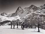 Winternostalgie in Mürren. Die Gruppe schaut dem Skilehrer gespannt zu. Im Hintergrund stehen die verschneiten Eiger und Mönch.