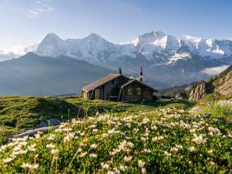 Die Lobhornhütte im Frühling, mit dem Dreigestirn Eiger, Mönch und Jungfrau im Hintergrund.
