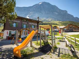 Le refuge Alpiglen à Grindelwald, avec son aire de jeux et l'Eiger en arrière-plan, par une journée estivale.