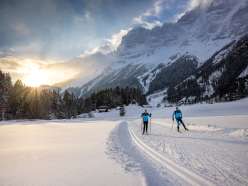 Bei Sonnenuntergang: Zwei Langläufer*innen unterwegs auf der Loipe in Guttannen.