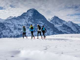 Zwei Läufer beim Winter Trail Running auf Grindelwald First, im Hintergrund der Eiger.