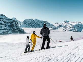 Skifahren im Skigebiet Grindelwald - Wengen. Der Skifahrer macht eine Pause und geniesst das Panorama mit Sicht auf das Nebelmeer.