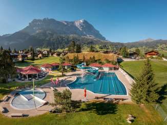Das Freibad in Grindelwald aus der Vogelperspektive mit Häuser und Eiger im Hintergrund.