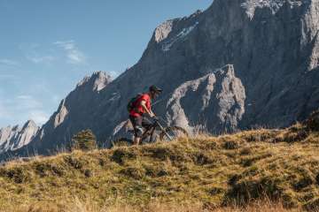 A man on a mountain bike is riding up a bike trail.