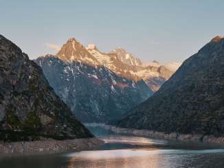 Aussicht über den Grimselsee mit Bergspitzen im Abendrot.