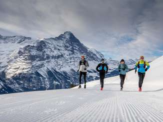 Deux coureurs lors d'une course de trail hivernale à Grindelwald First, avec l'Eiger en arrière-plan.