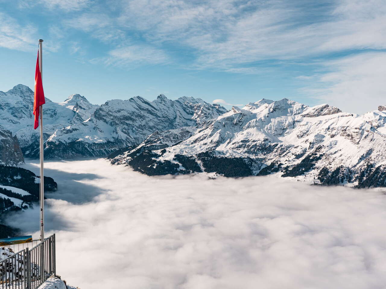 View from Männlichen over the sea of fog in the Lauterbrunnen valley. The snow-covered mountain panorama can be seen in the background.