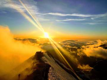 Die untergehende Sonne ermöglich wunderschöne Aufnahmen vom Schilthorn. Die umliegende Bergwelt versinkt in den golden gefärbten Wolken.