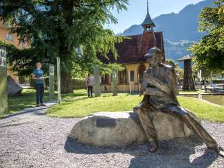 Vor dem Sherlock Holmes Museum in Meiringen steht eine Statue vom Meister-Dedektiv. Die Touristen lesen sich in die Geschichte von Sherlock Holmes ein.