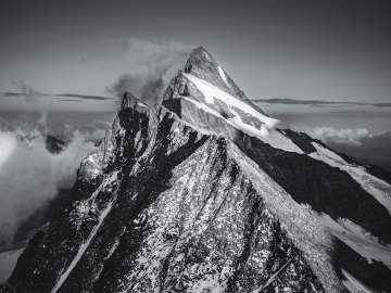 Photo en noir et blanc du Finsteraarhorn, prise depuis la crête, avec un panorama montagneux. 