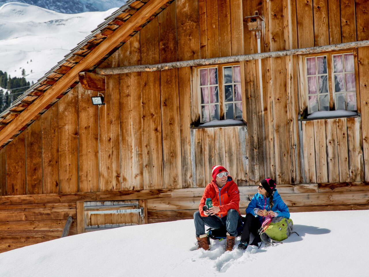 Winterwanderung auf verschneiten Winterwanderwegen rund um Grindelwald. Die Wanderer geniessen den sonnigen Tag bei einem Rast und etwas zu Trinken.