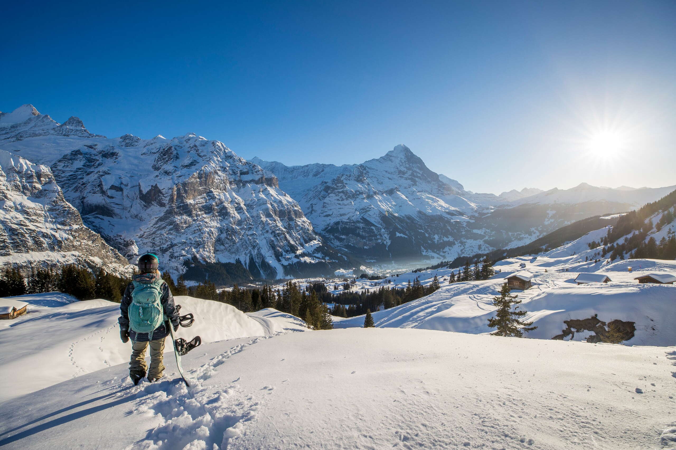 Snowboarder unterwegs im Skigebiet Grindelwald First. Sie hinterlassen ihre Supern im frischen Pulverschnee und geniessen die Aussicht auf das imposante Bergpanorama.