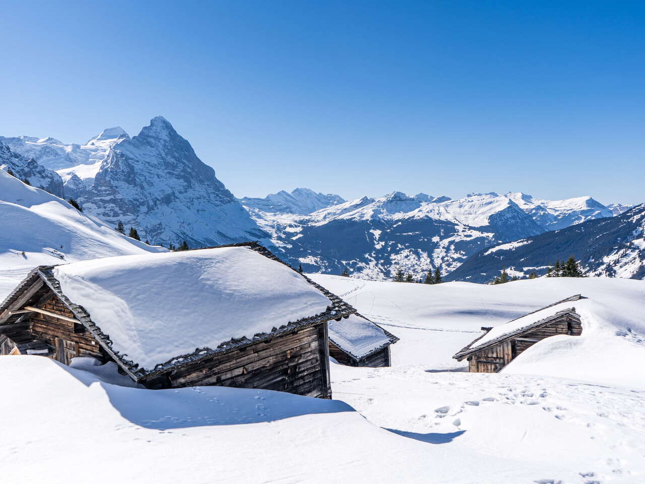 Verschneite Alphütten inmitten des imposanten Bergpanoramas ob Grindelwald.